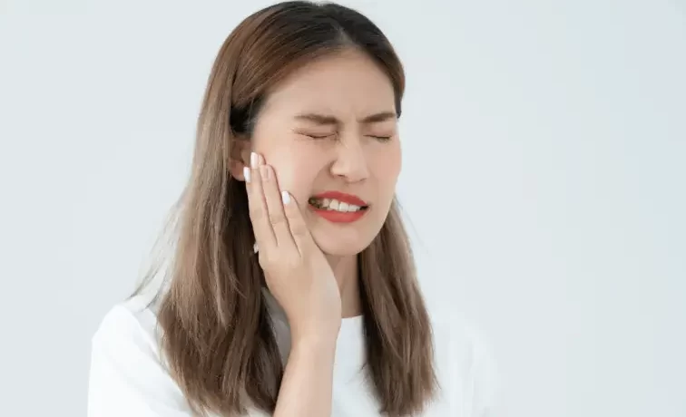 A woman experiencing tooth sensitivity and pain after a dental filling procedure