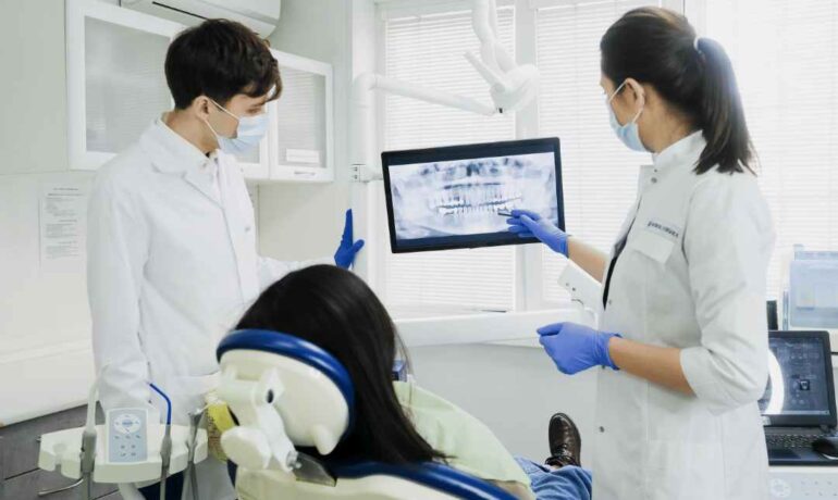 Two dentists examining a patient's dental fillings with imaging